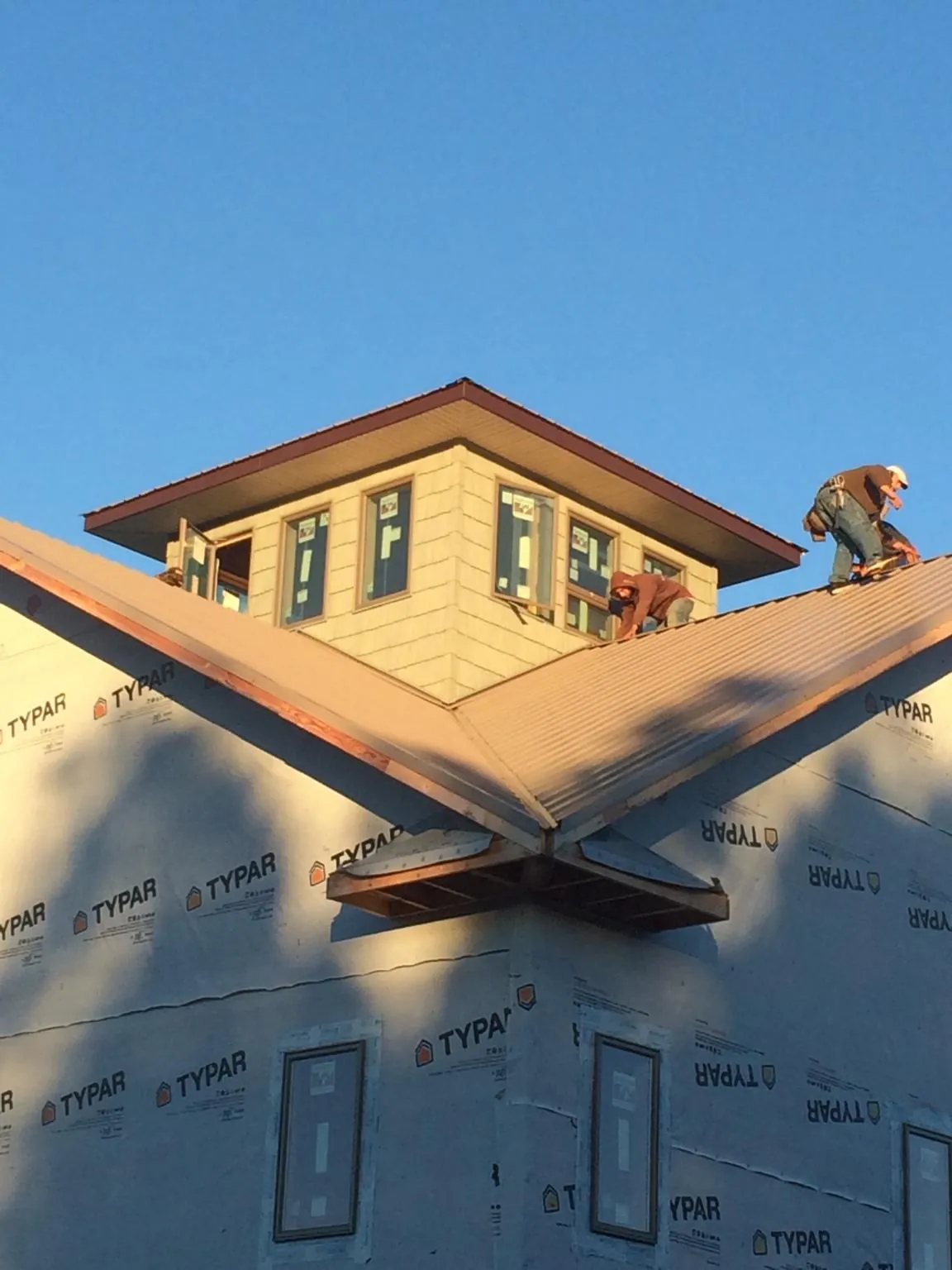 Roofers working around a rooftop cupola on a new metal roof at sunset — Roof Waterproofing in Montezuma by Roofing Brothers